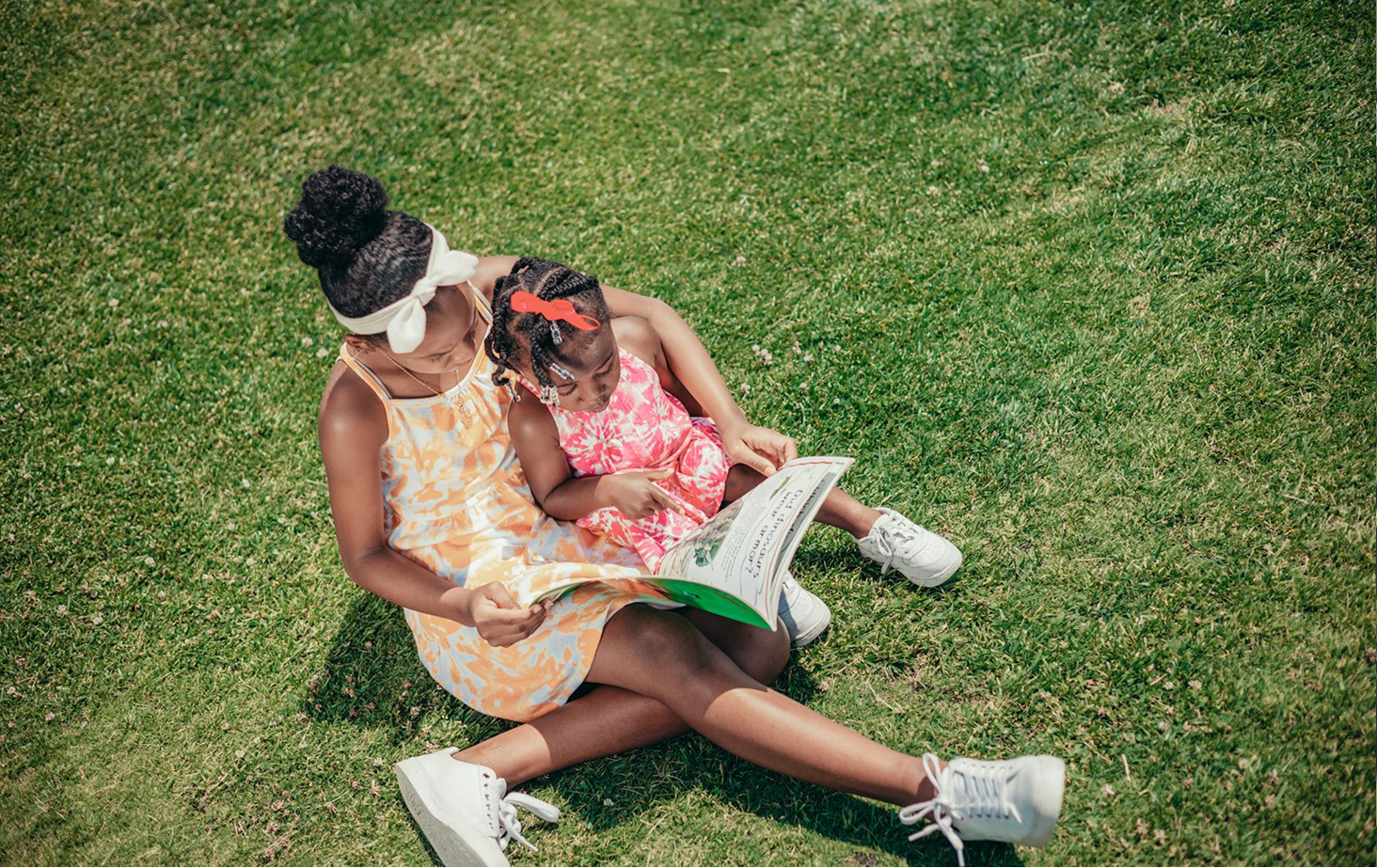 Two children reading together on grass